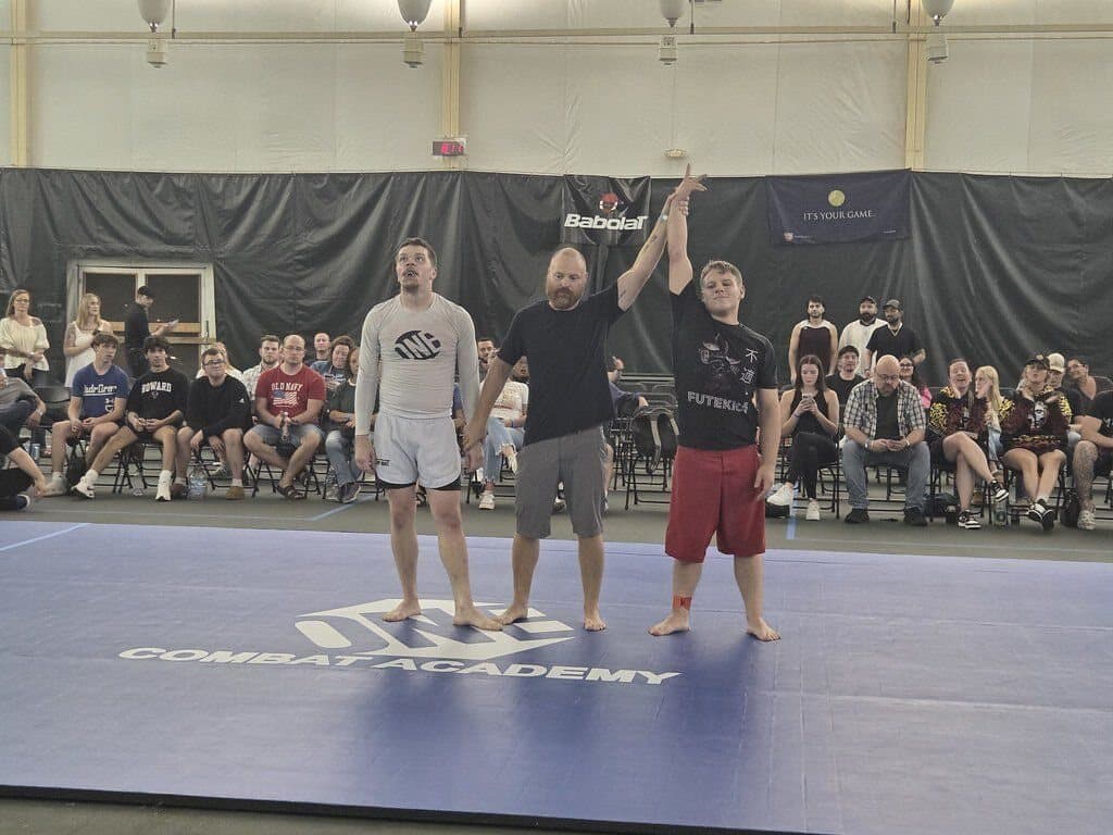 A referee raising a Misfits grappler's hand at a tournament