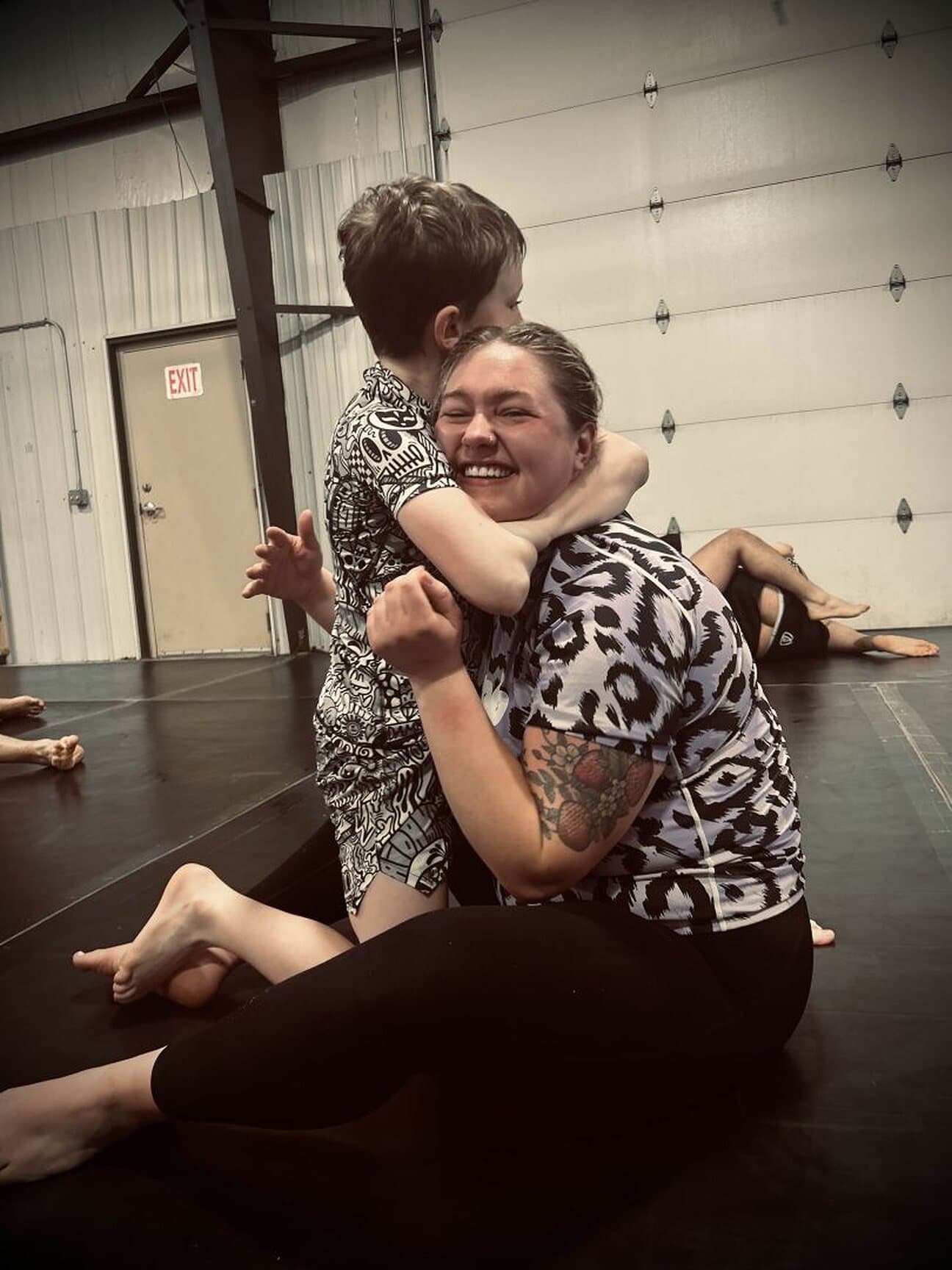 A young grappler hugging a coach on the mat