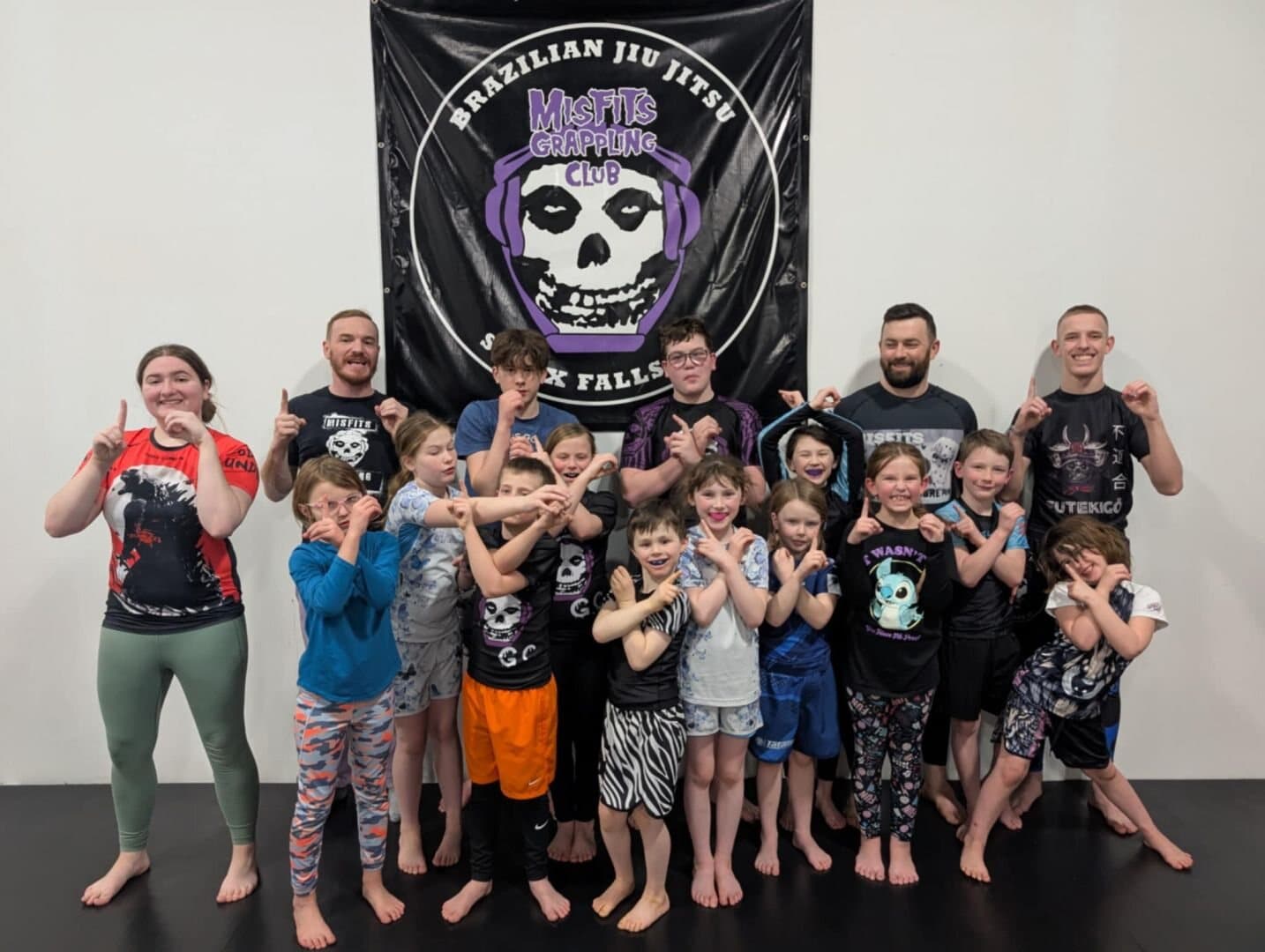 Kids and coaches together in front of the Misfits Grappling Club banner