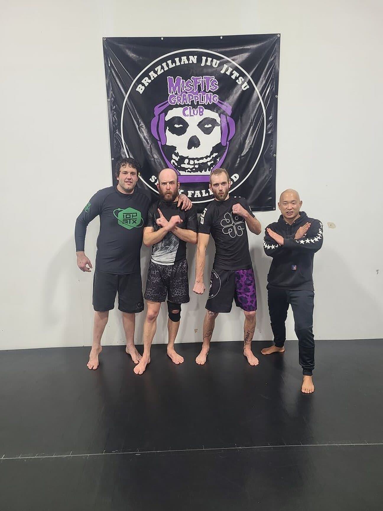 Four Misfits grapplers in front of the club banner